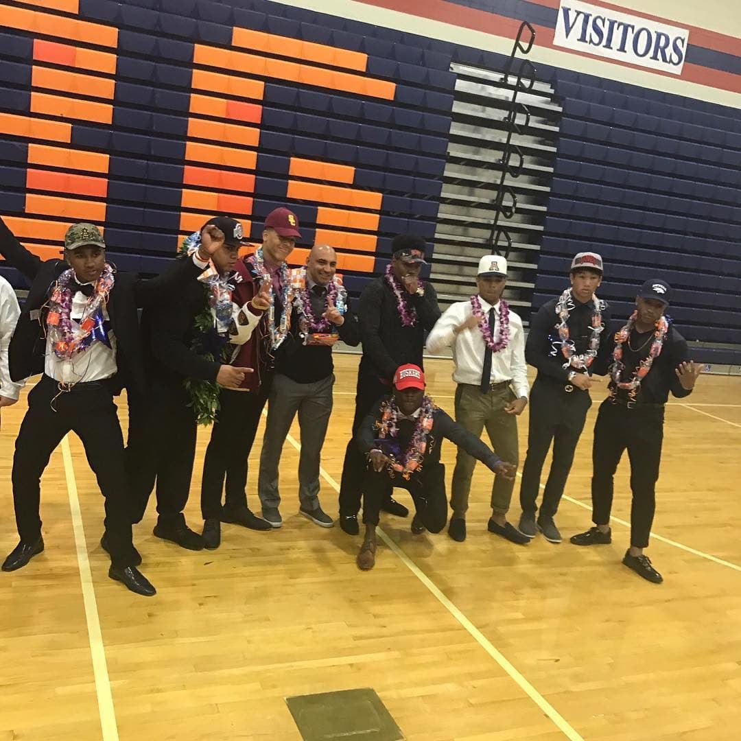 National Signing Day — college caps and leis in the gym. USC, Arizona, Nebraska in the room.